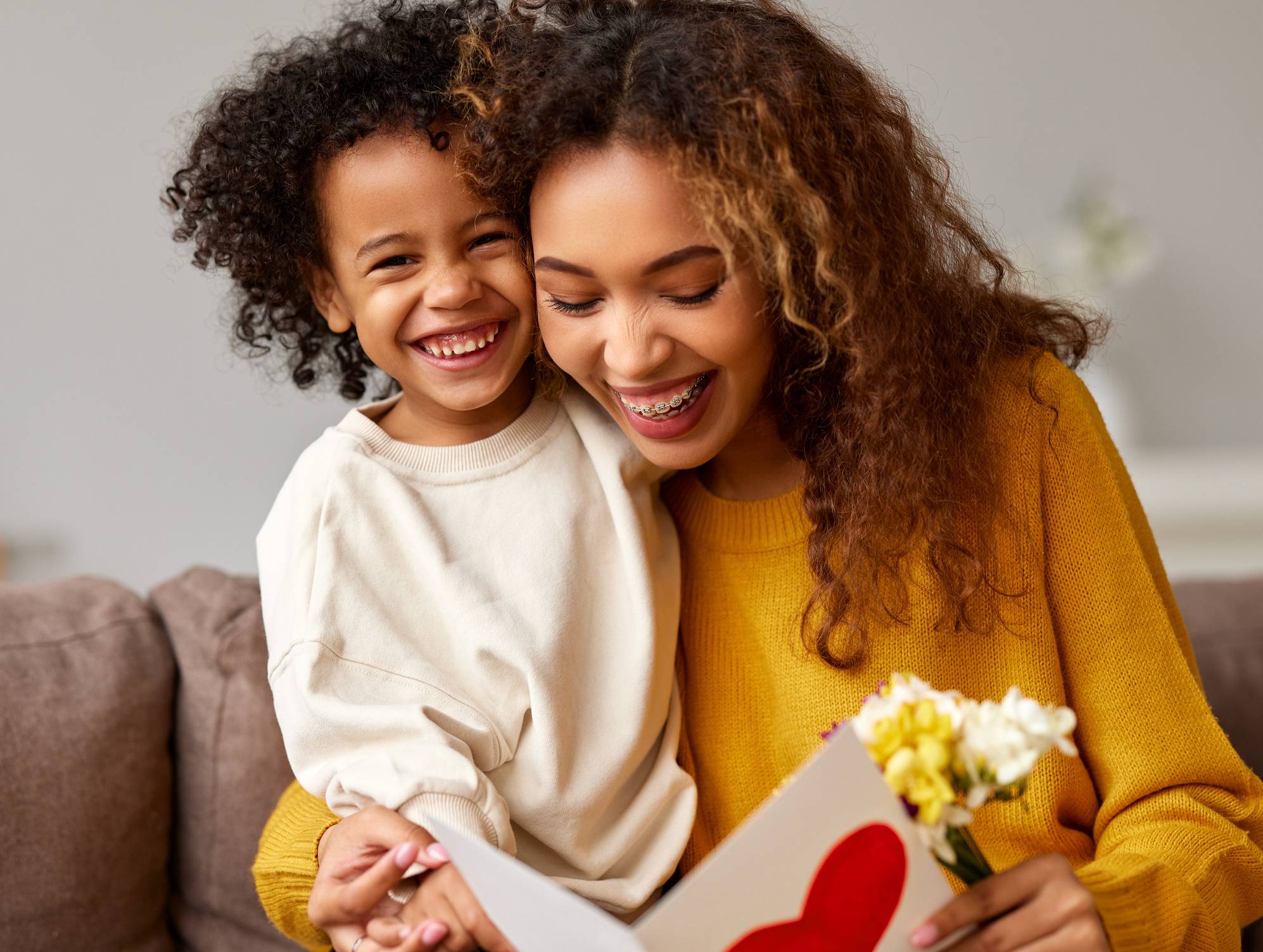 Young mixed race woman getting congratulations from son on Mothe