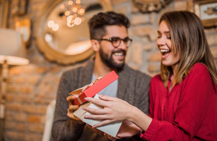 Cheerful young woman receiving a gift from her boyfriend.